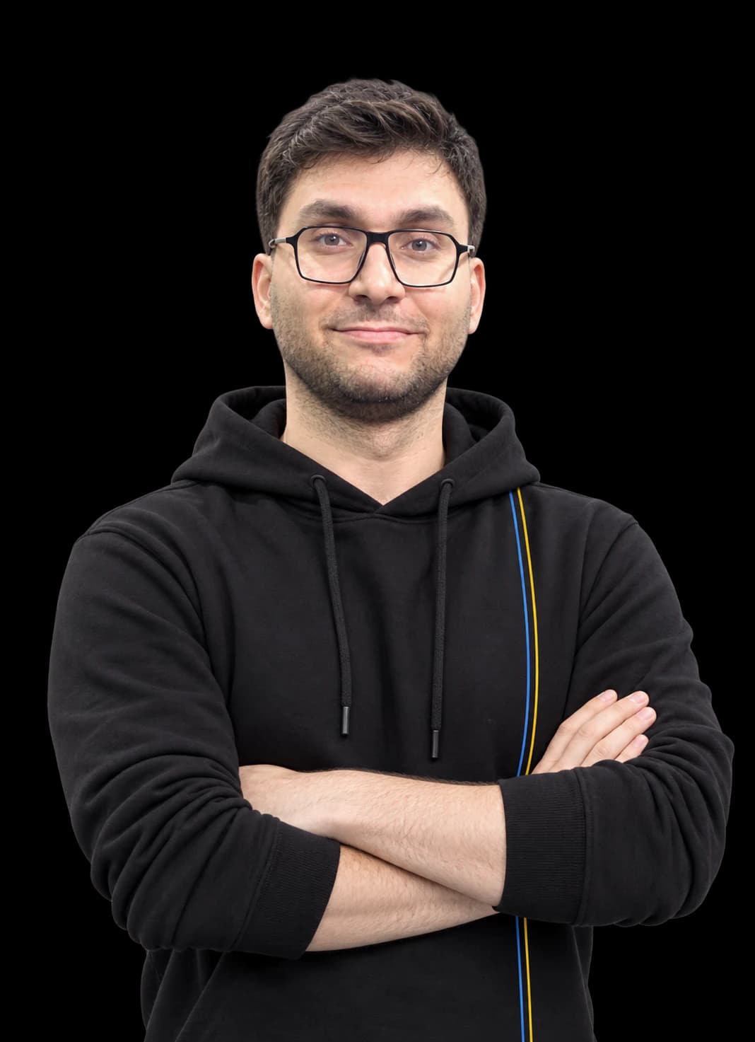 Vahid Aslani, fundador de Axiean, sonriendo con los brazos cruzados. Lleva gafas y una sudadera negra con una fina franja azul y amarilla.